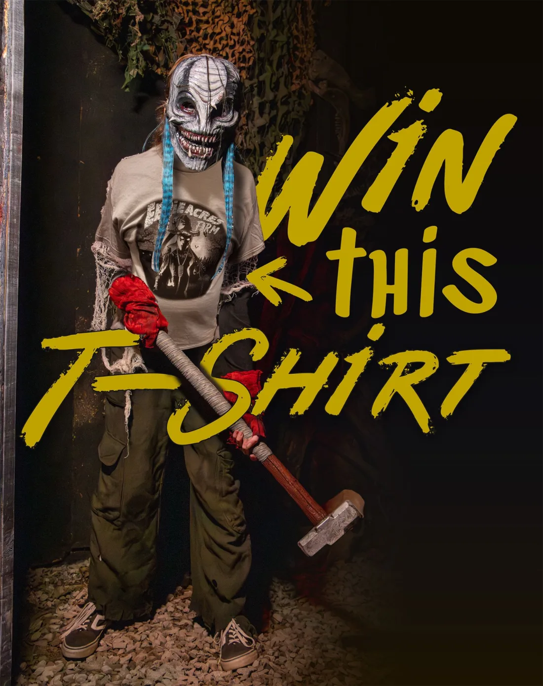 An Eerie Acres Farm actor in a cracked white mask holding a sledgehammer and wearing the 2026 giveaway shirt, with the words Win This T-Shirt painted beside them